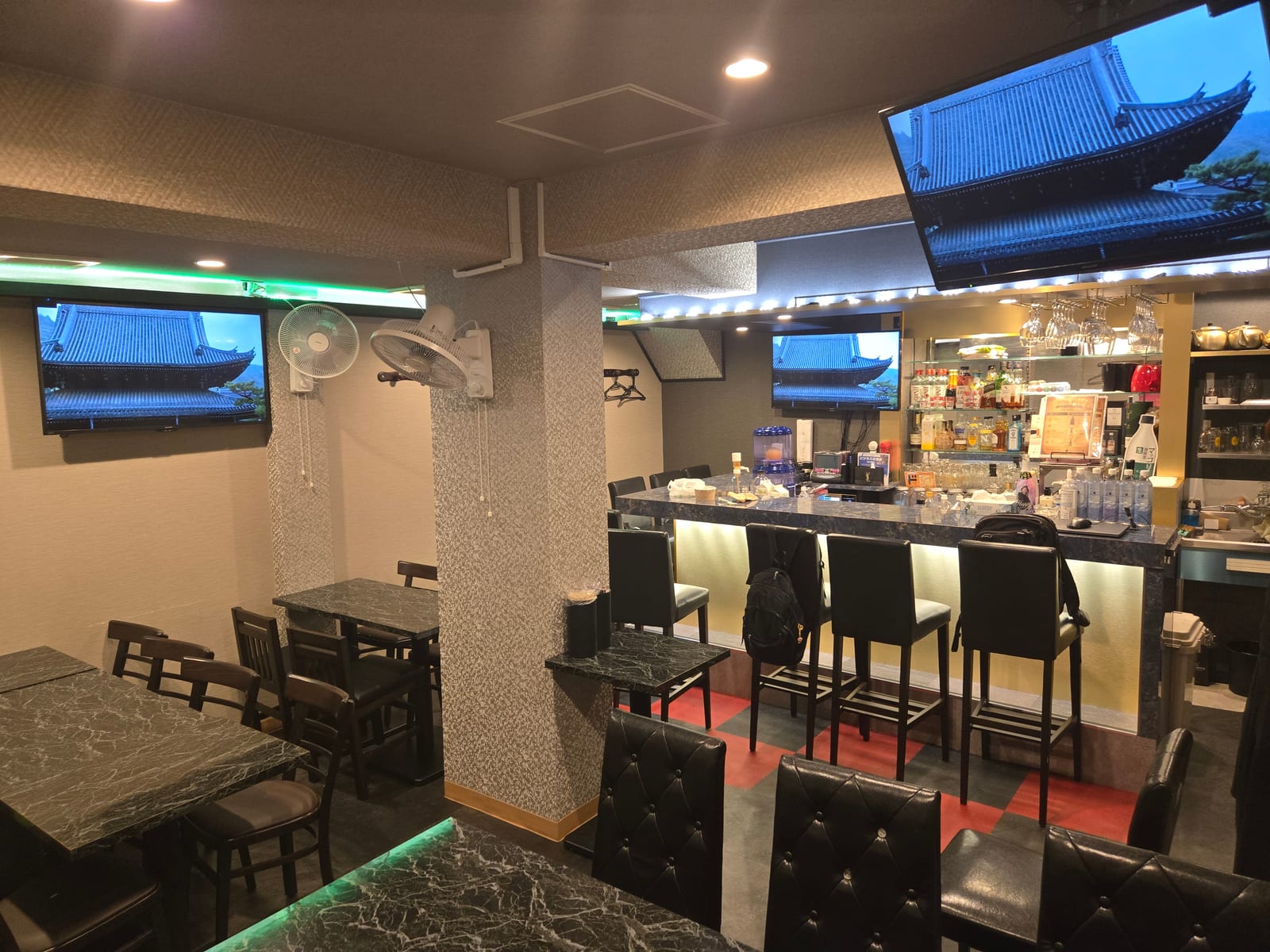 テーブル席とカウンター、壁のテレビが見える、上野の隠れ家BARの店内